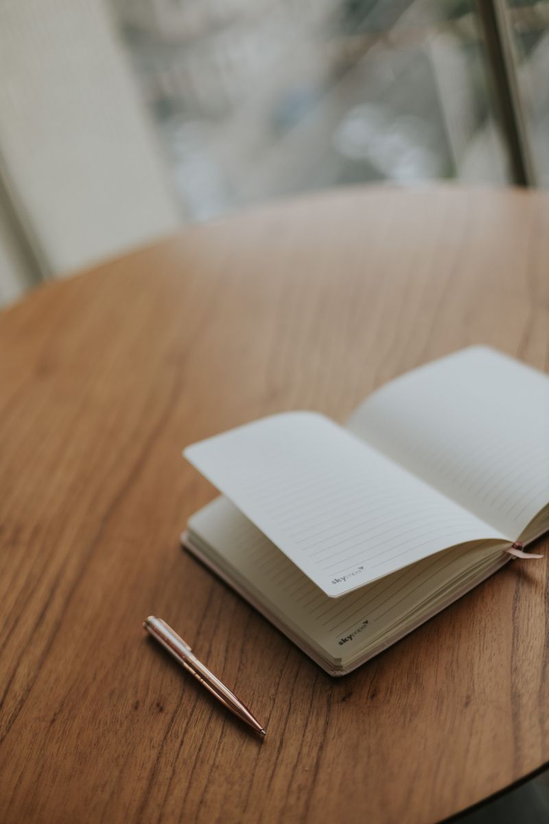An open diary with a pen on a wooden desk